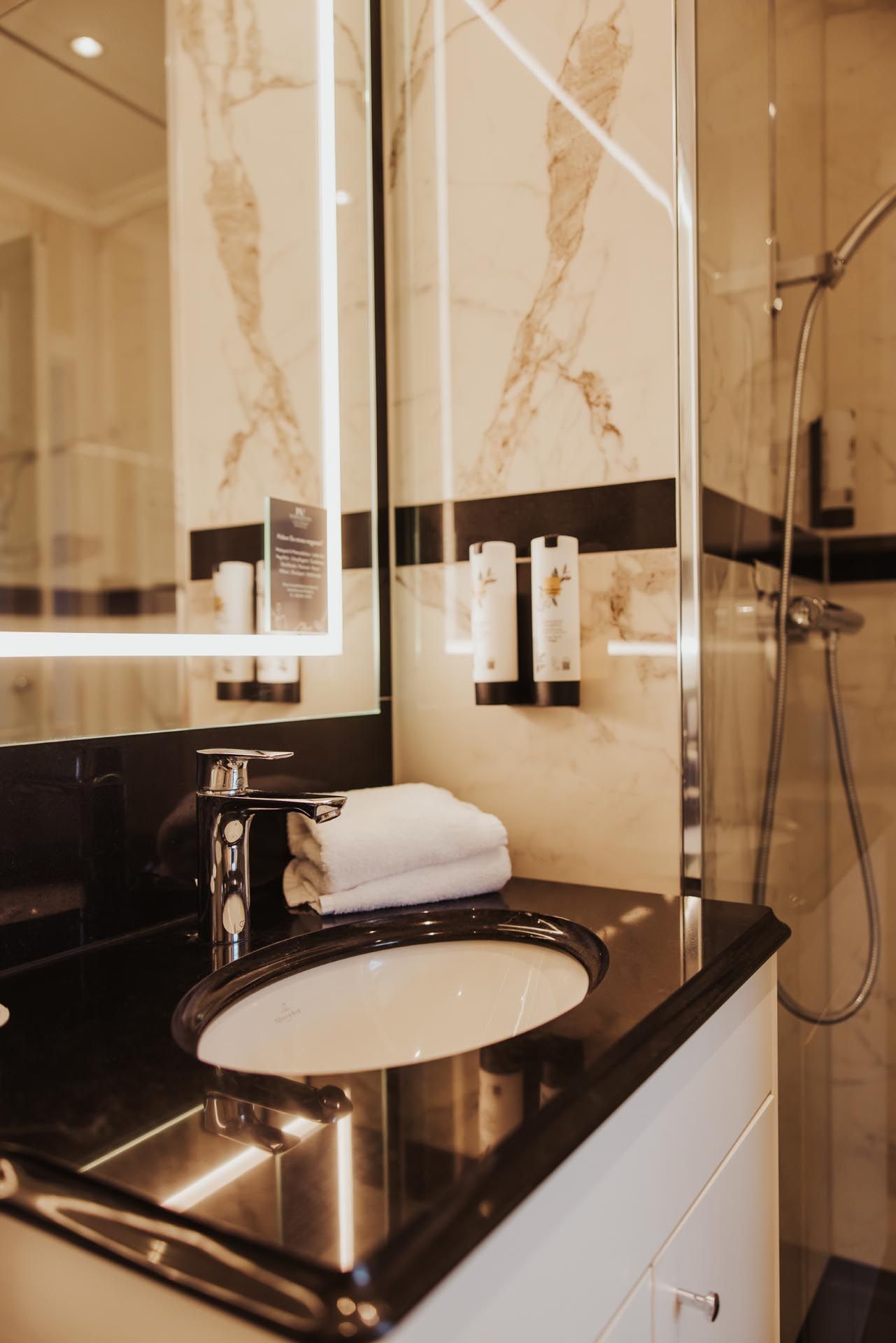 Badezimmer Marmor, Waschbecken, Duschecke und Spiegel.