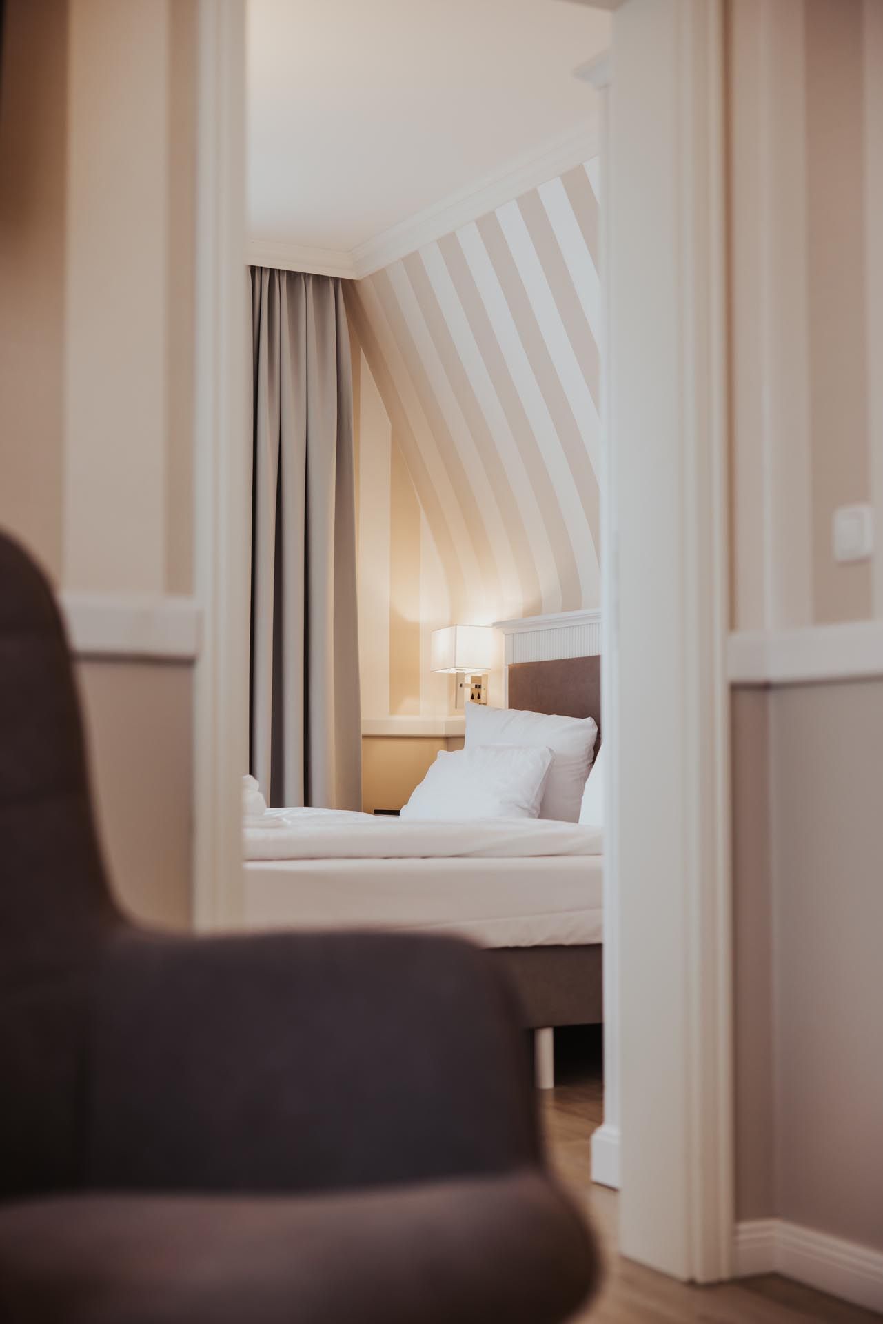 Schmaler Blick durch eine Tür in Richtung Schlafzimmer mit einem Bett.