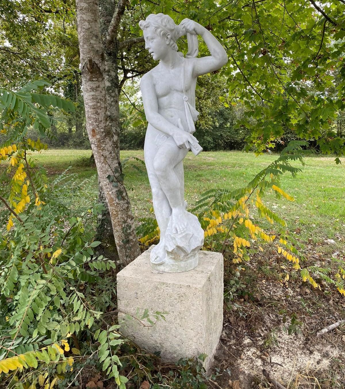 Une statue en pierre blanche dans un jardin