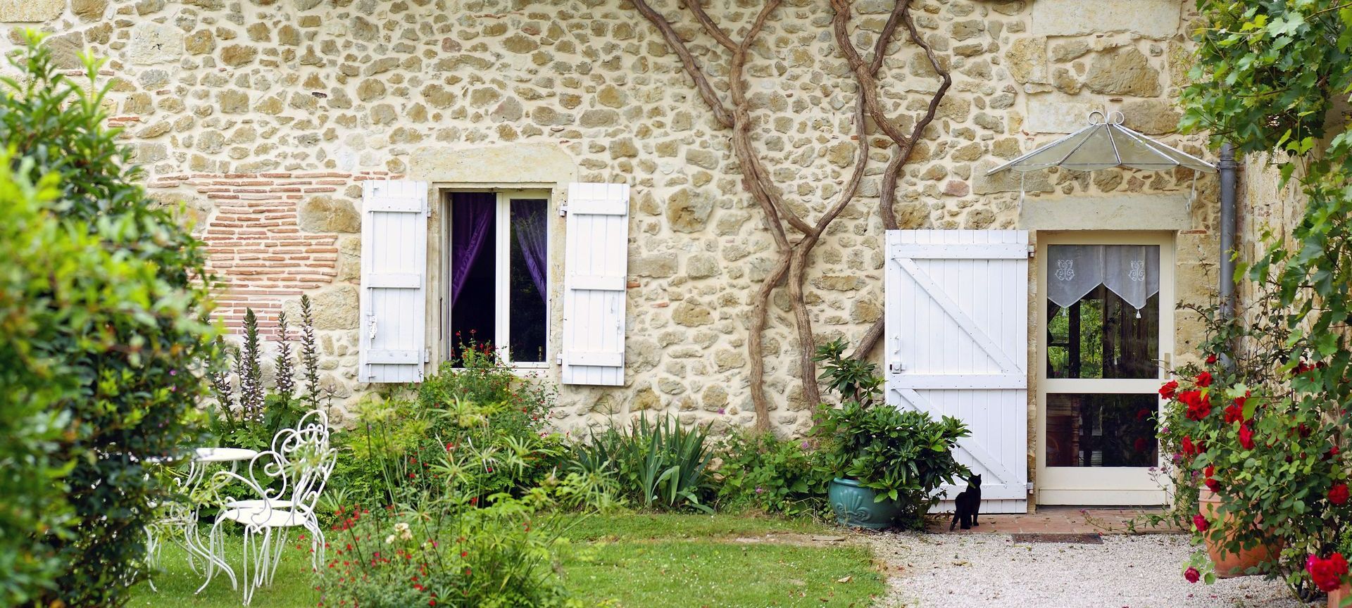 Une maison avec une façade en pierre et de la végétation grimpante