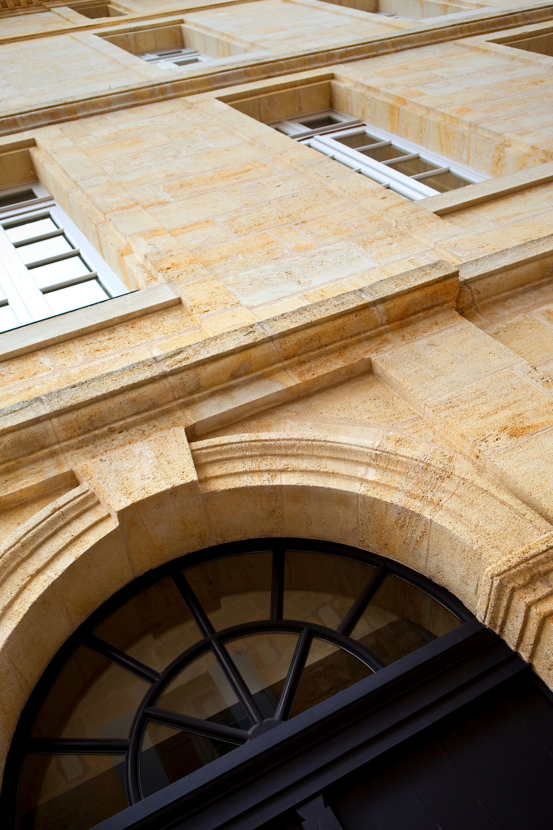 Façade en pierre vue de côté et gros plan sur une arche au-dessus de la porte