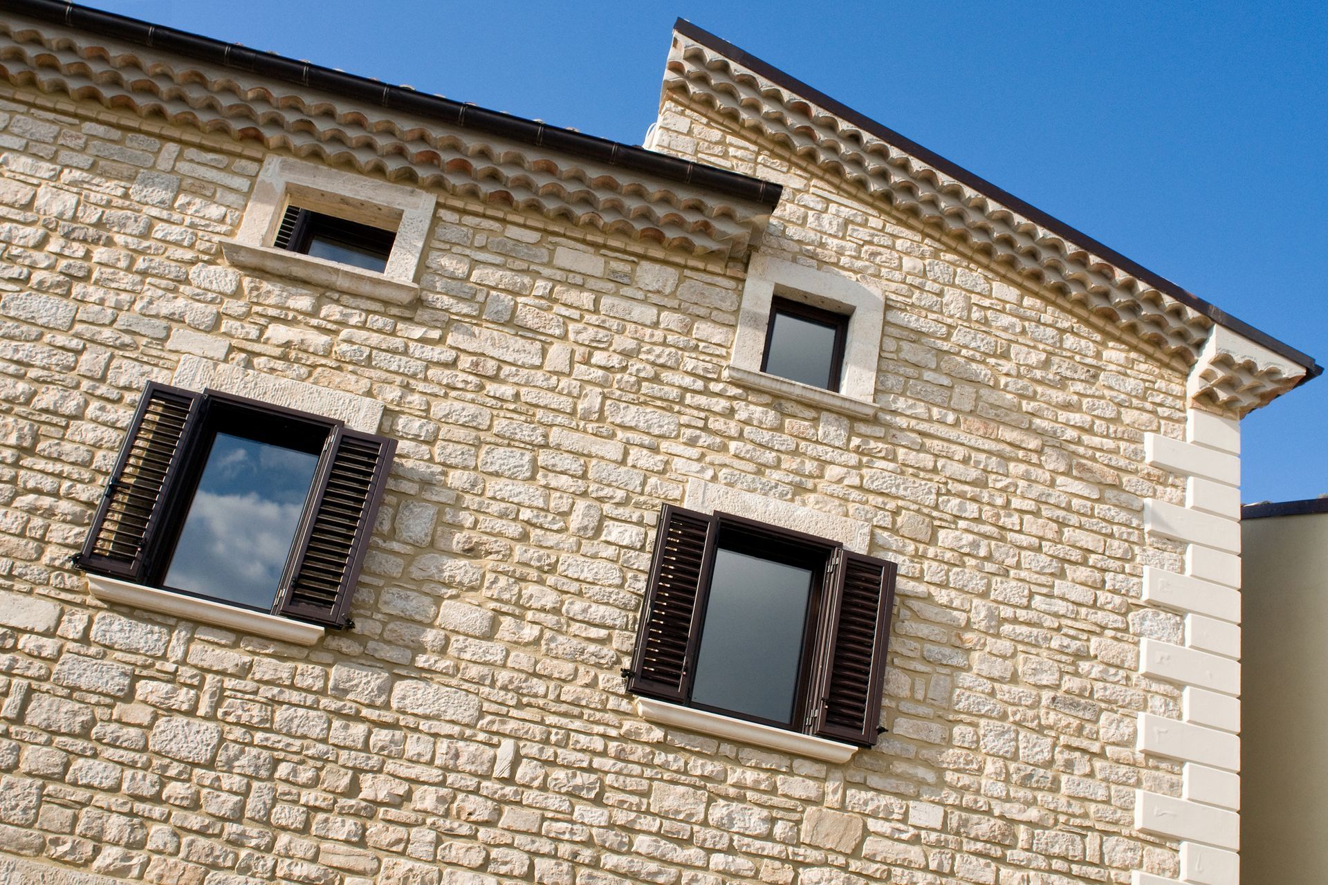 Une façade en pierre d'une maison avec des persiennes en bois