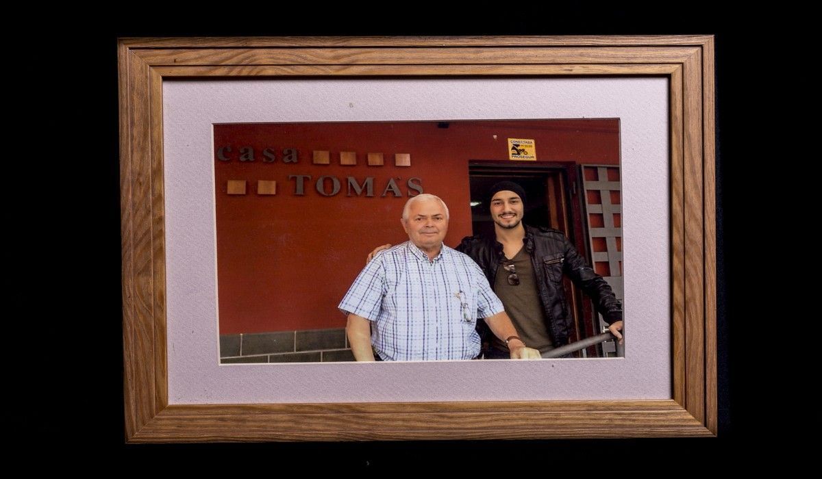 Dos hombres posan para una foto frente a un edificio que dice Tomas