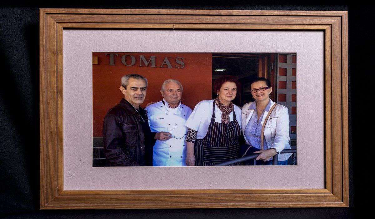 Una fotografía enmarcada de tres personas frente al restaurante Thomas.