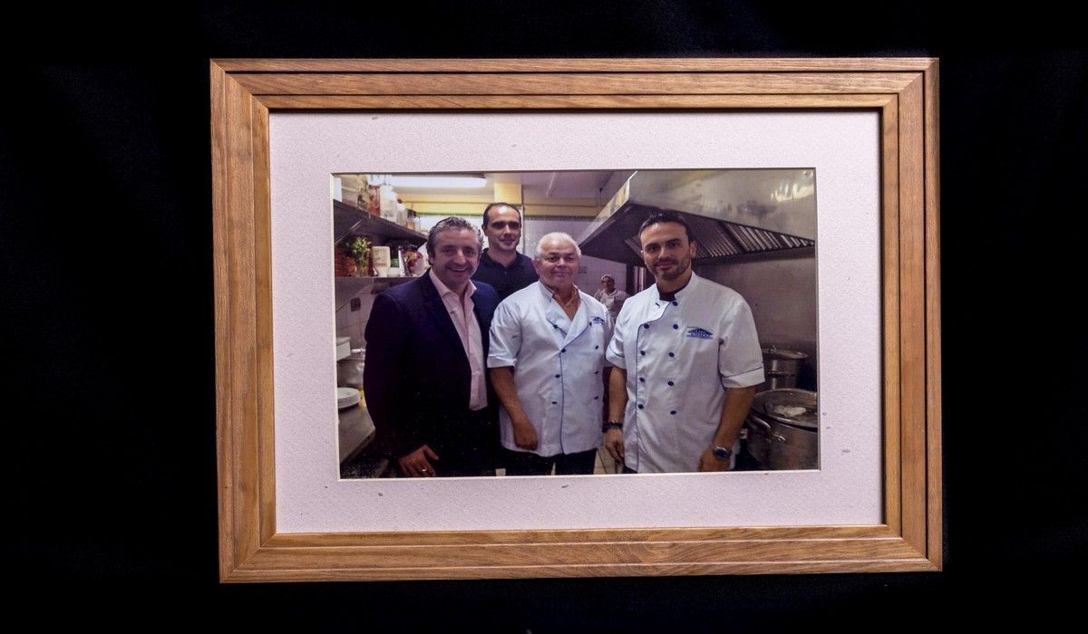 Una fotografía de cuatro hombres en una cocina en un marco de madera.