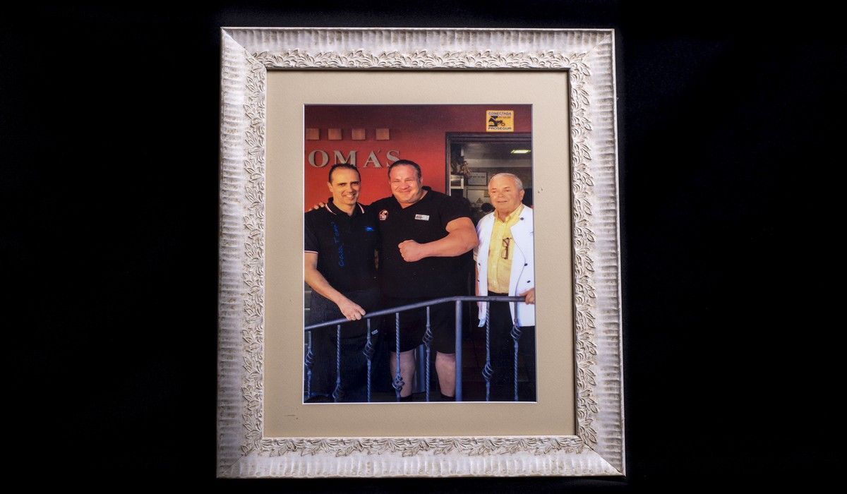 Una fotografía enmarcada de tres hombres de pie uno al lado del otro.