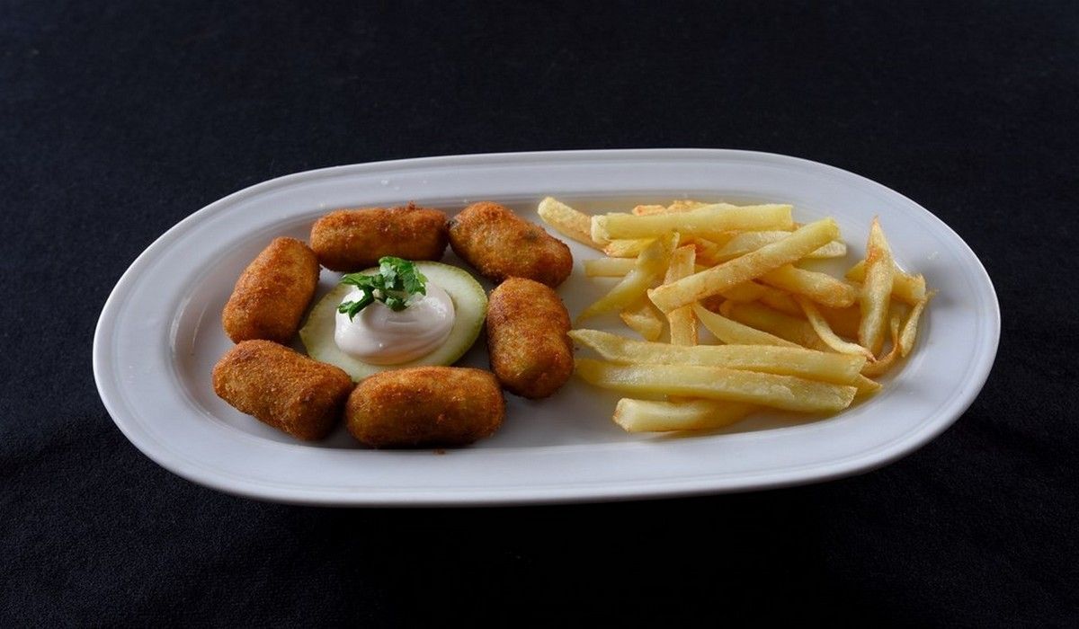 Un plato blanco cubierto con comida frita y papas fritas.
