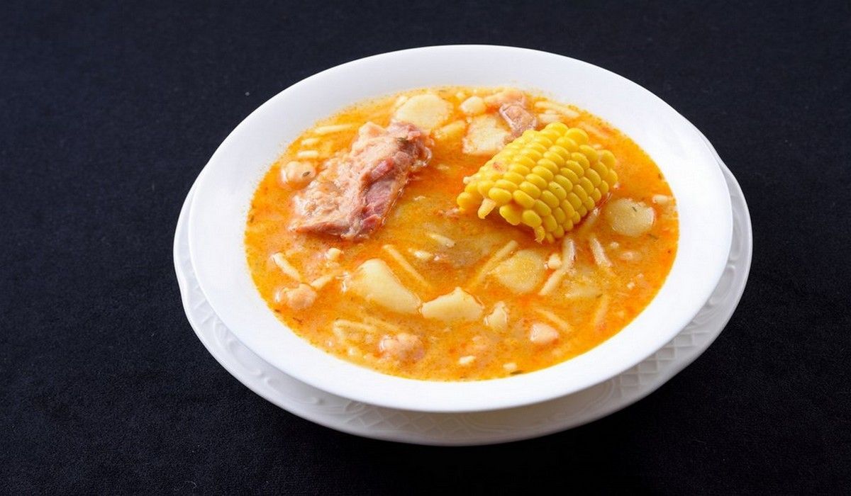 Un tazón de sopa con mazorcas de maíz encima