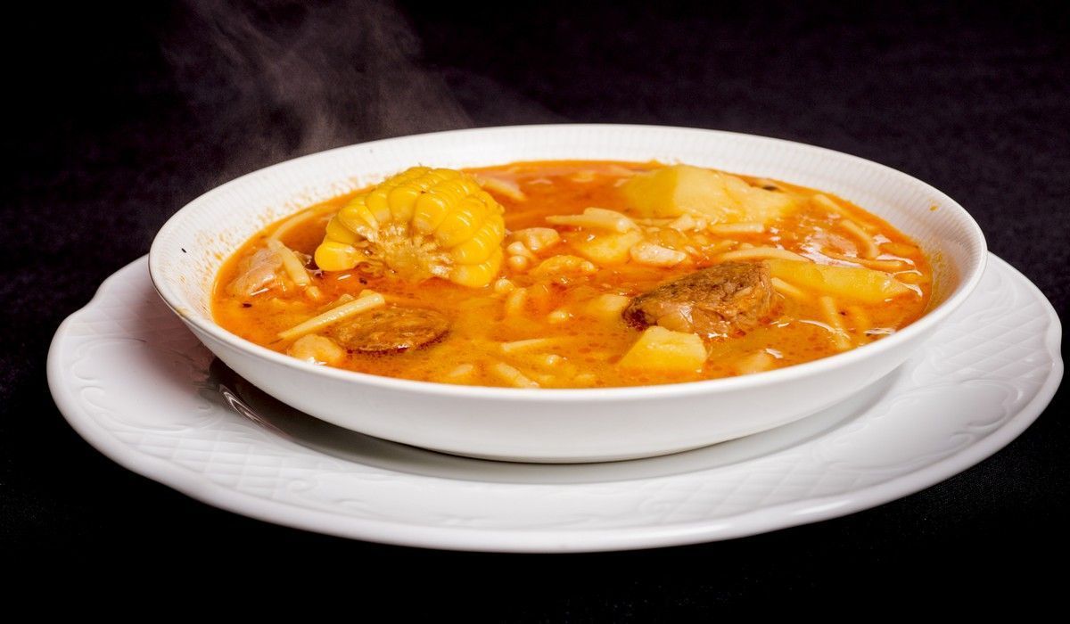 Un tazón de sopa en un plato blanco del que sale vapor.