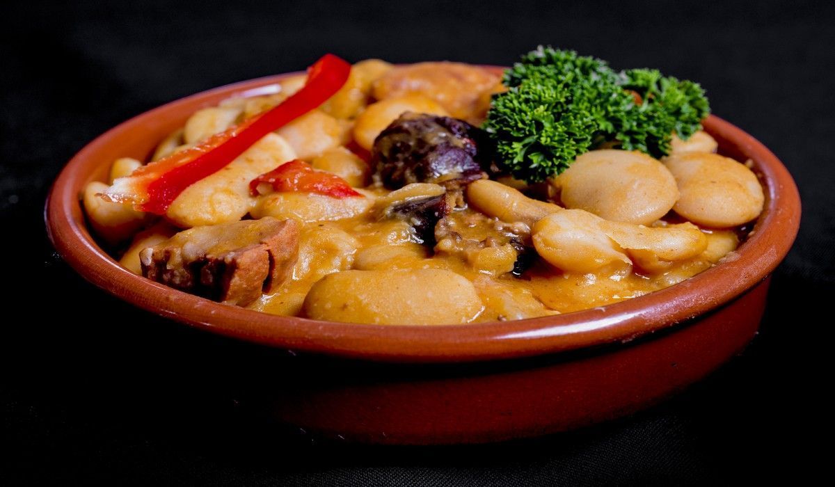 Un tazón de comida con frijoles y verduras en una mesa.