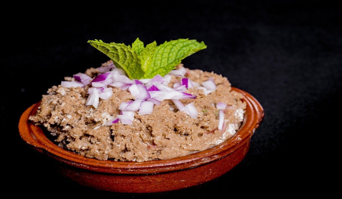 Un tazón de comida con cebollas y una hoja de menta encima.