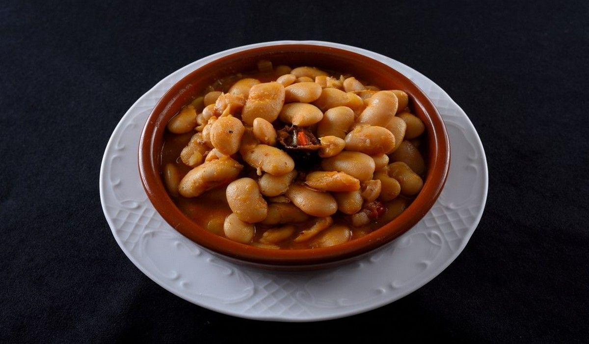 Un tazón de frijoles está en un plato blanco