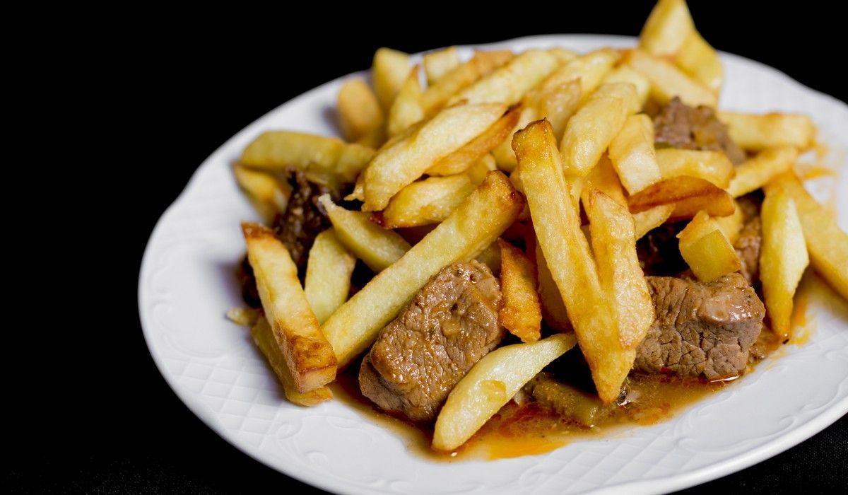 Un plato blanco cubierto con papas fritas y carne.