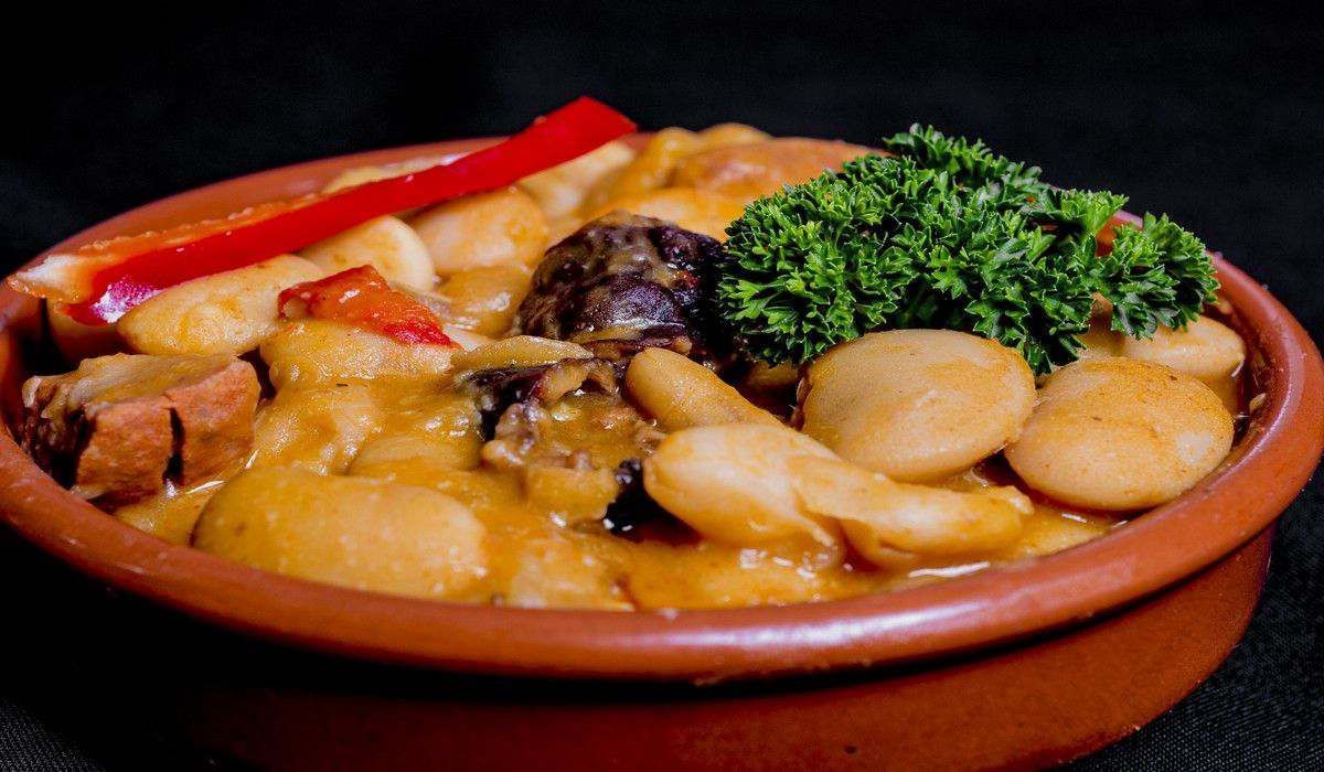 Un tazón de comida con frijoles y verduras en una mesa.