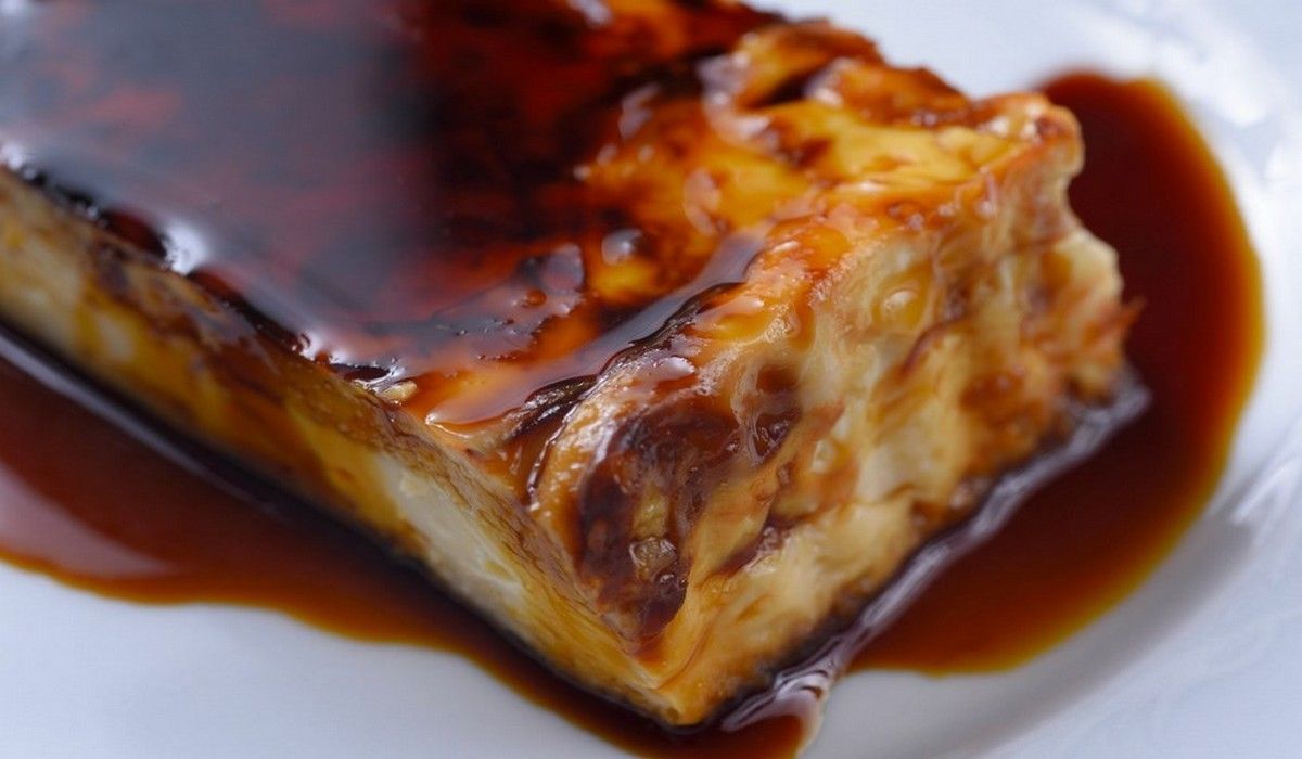 Un trozo de pastel con salsa en un plato blanco.