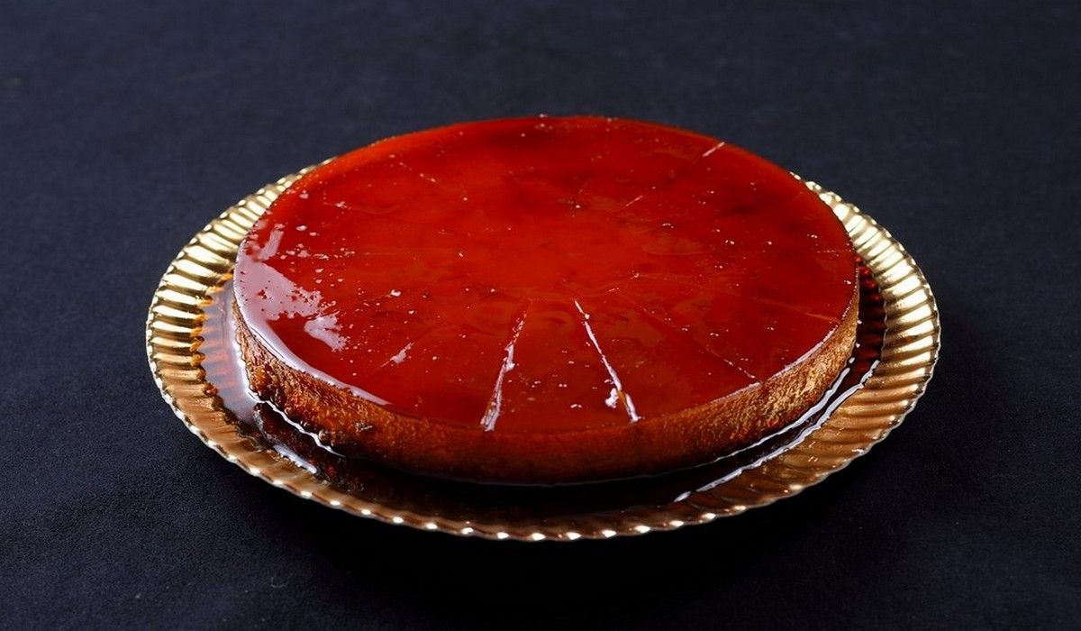 Una tarta de queso y fresa está en un plato dorado sobre una mesa negra.