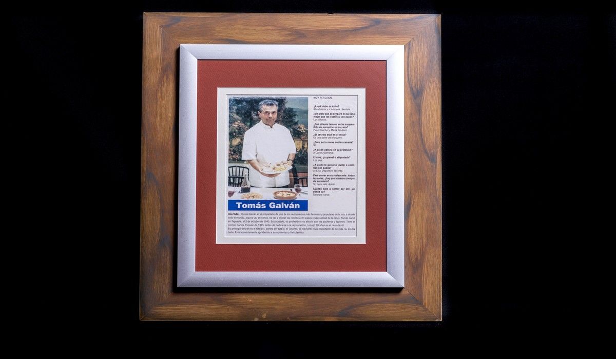 Una fotografía de un hombre con una camisa blanca está enmarcada en un marco de madera.