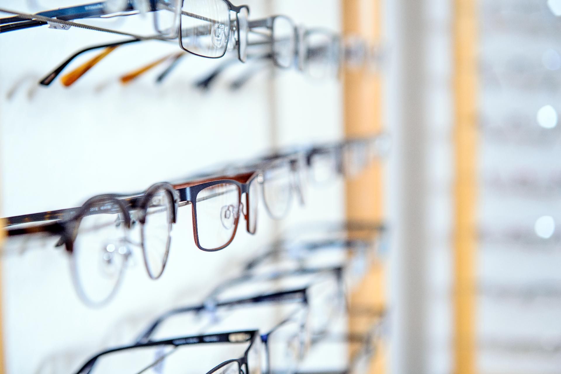 Reihen von Brillen, ausgestellt an einem Wandregal in einem hellen Optikergeschäft