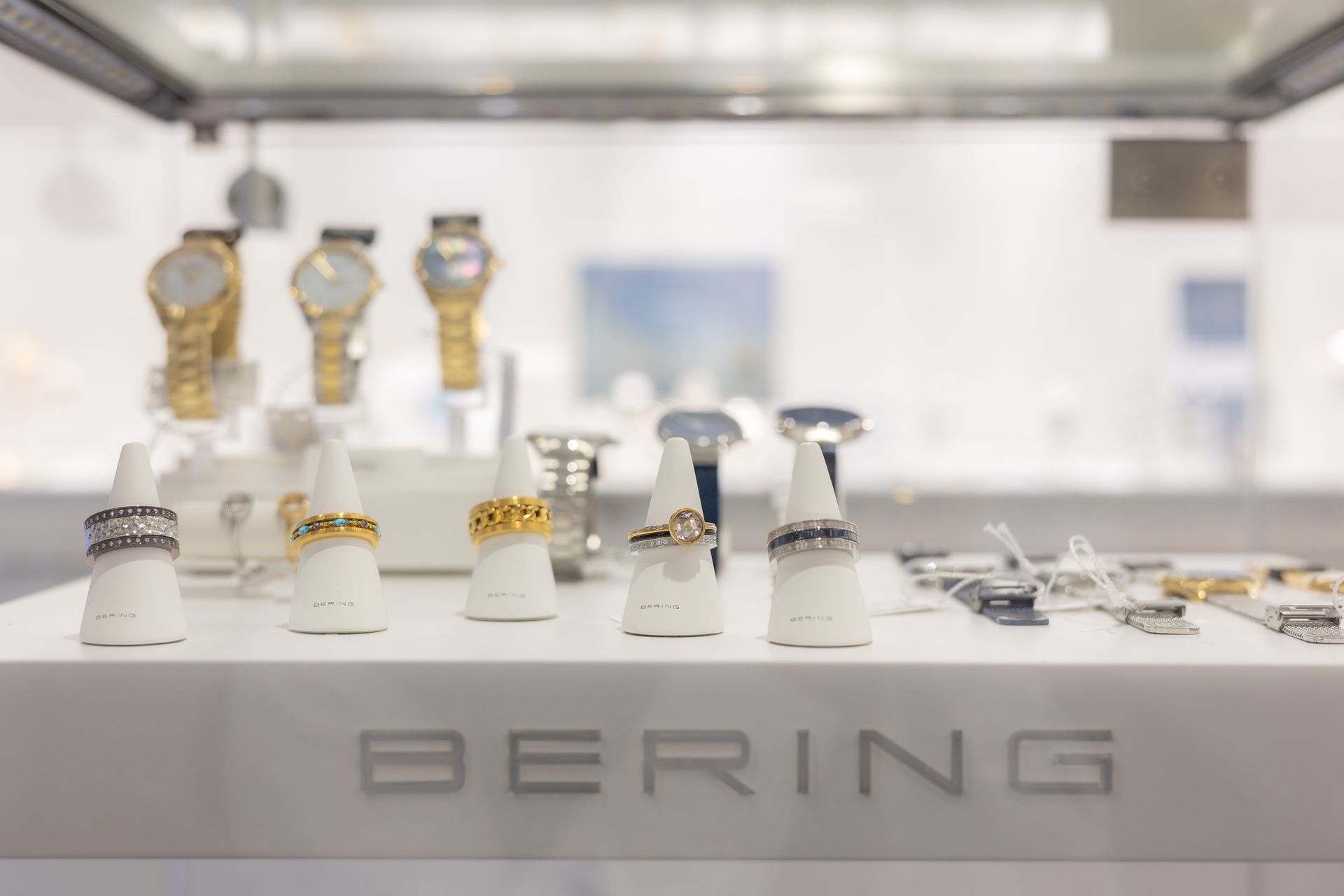 Uhrenvitrine mit weißen und goldenen BERING-Uhren auf einem Verkaufstisch