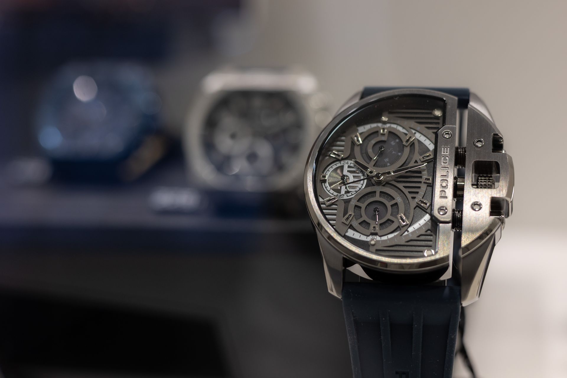 Luxuriöse Skelett-Armbanduhr mit schwarzem Armband vor verschwommenem Regalhintergrund