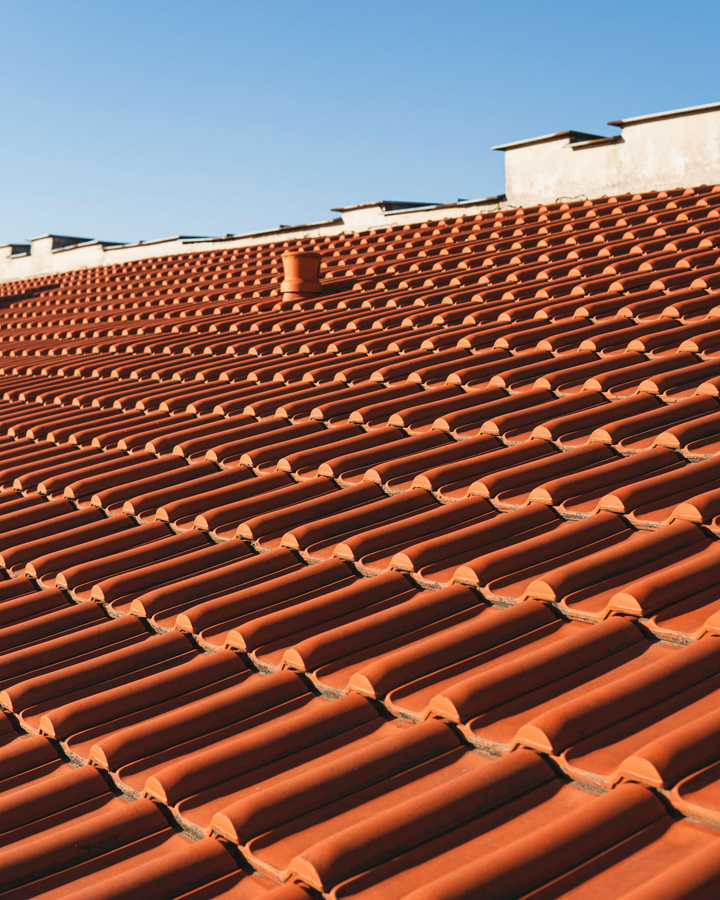 Gros plan sur un toit de tuiles rouges avec un ciel bleu clair en arrière-plan.