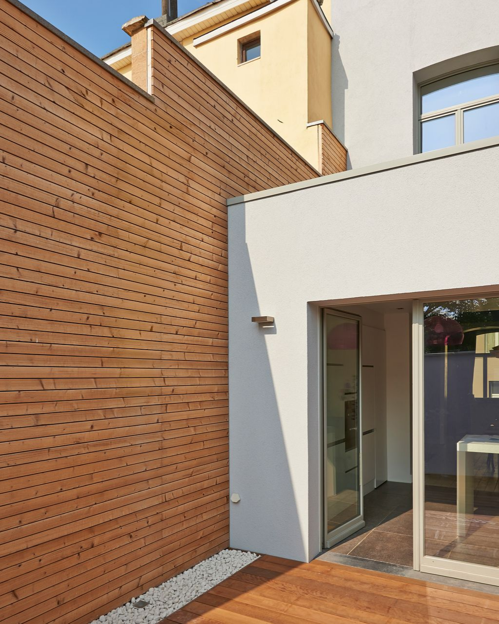 Un bâtiment avec un revêtement gris, une fenêtre blanche et un ciel d'un bleu limpide.