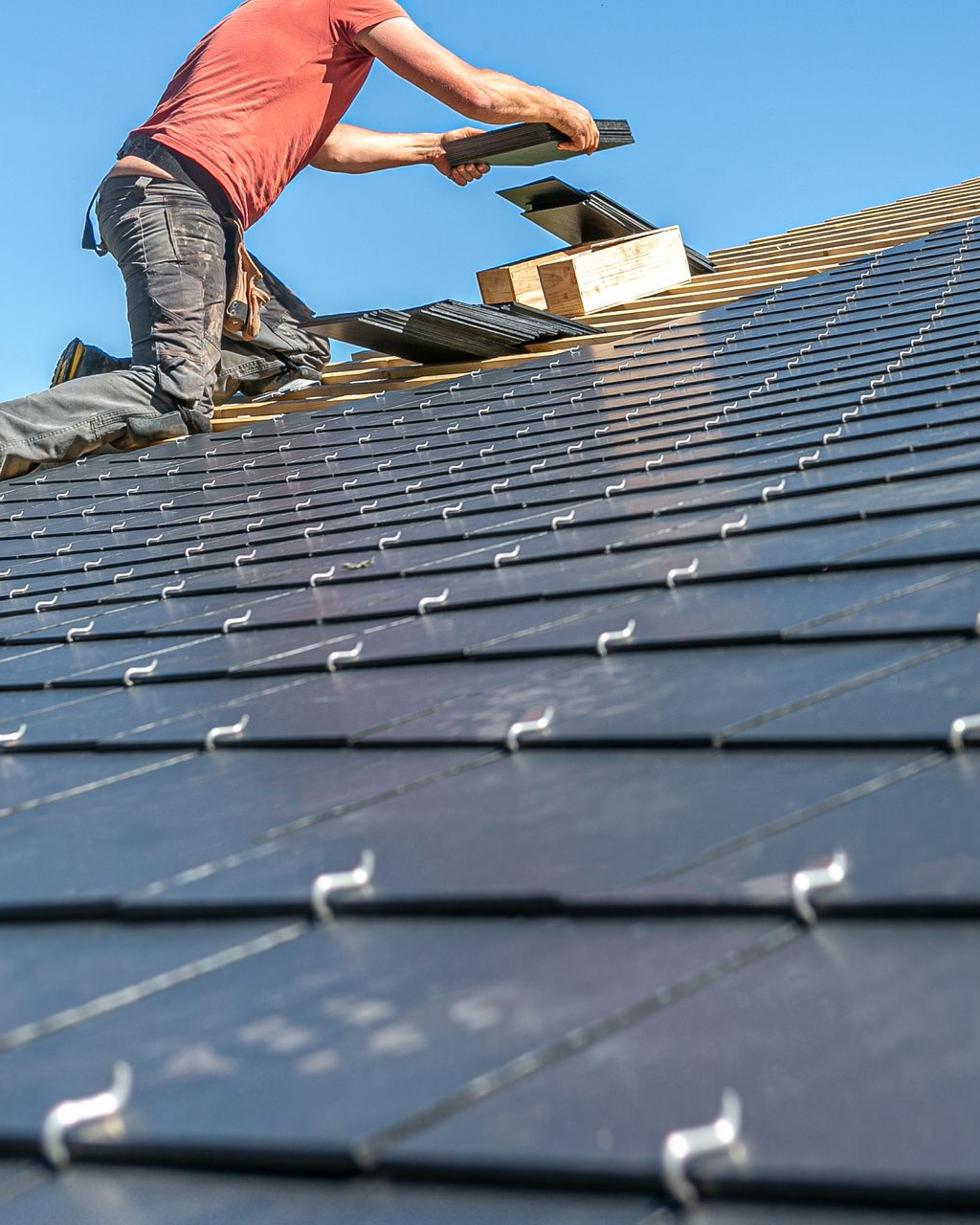 Toits de tuiles rouge-orangé sur un bâtiment avec un mur de pierre en arrière-plan.