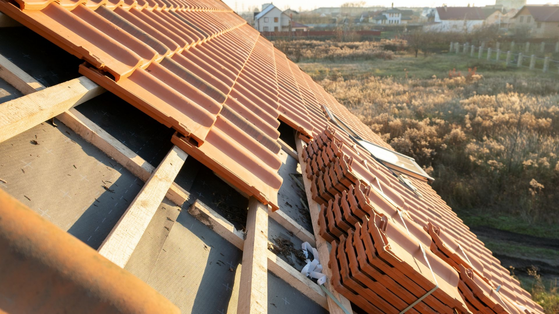 Pose de tuiles sur une charpente en bois. Tuiles brunes, cadre naturel.