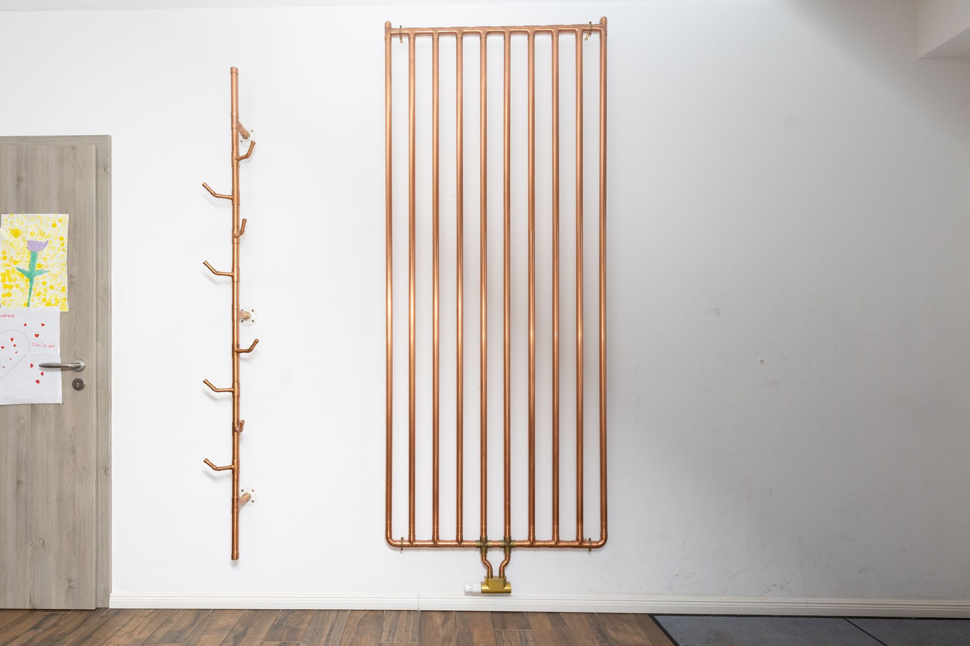 Ein Raum mit einem Kupferheizkörper und einer Garderobe an der Wand.