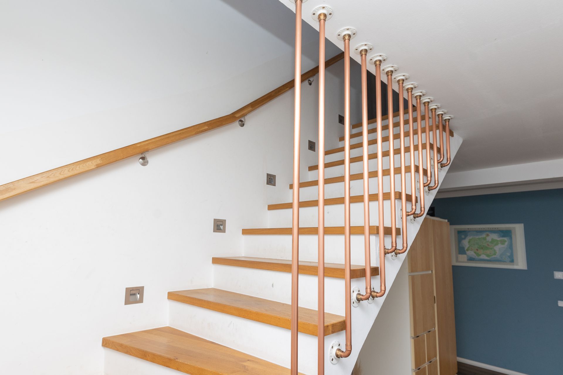 Eine Treppe mit Holzstufen und Kupfergeländer in einem Haus.