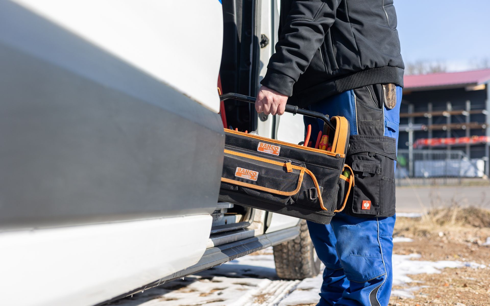 Ein Mann trägt eine Werkzeugtasche aus einem Lieferwagen.