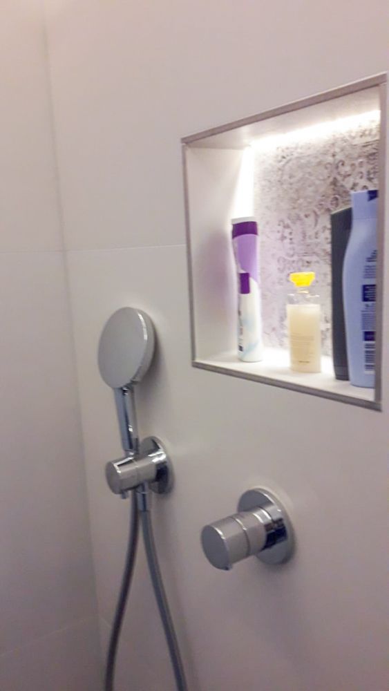 Ein Badezimmer mit einem Duschkopf und einem Regal mit Flaschen darauf.