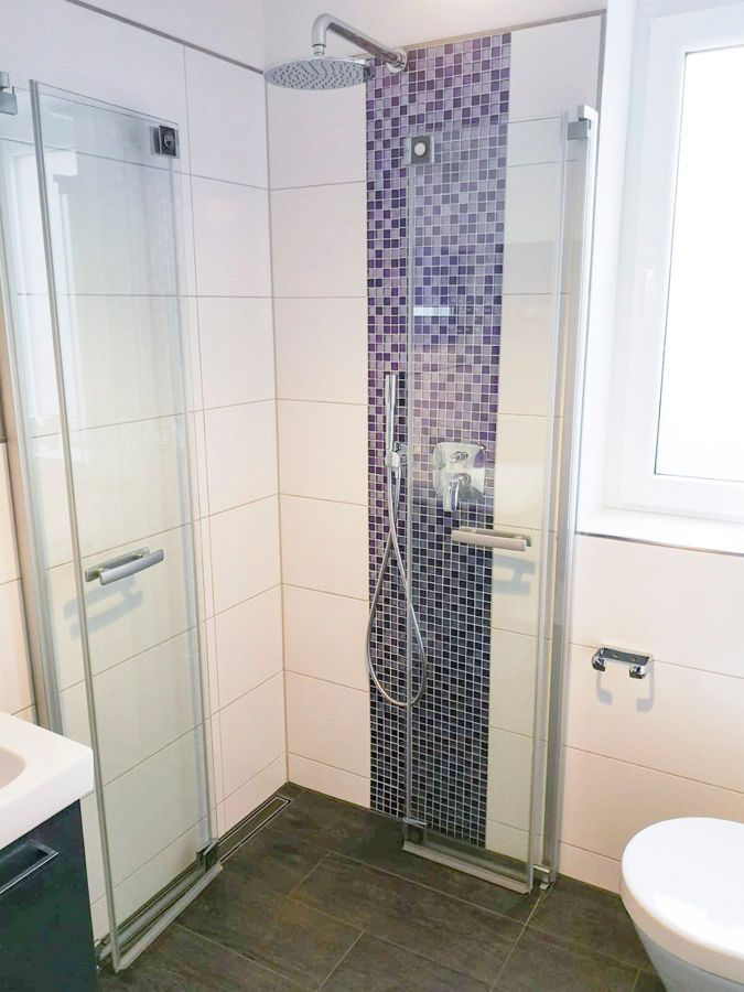 Ein Badezimmer mit ebenerdiger Dusche und Toilette