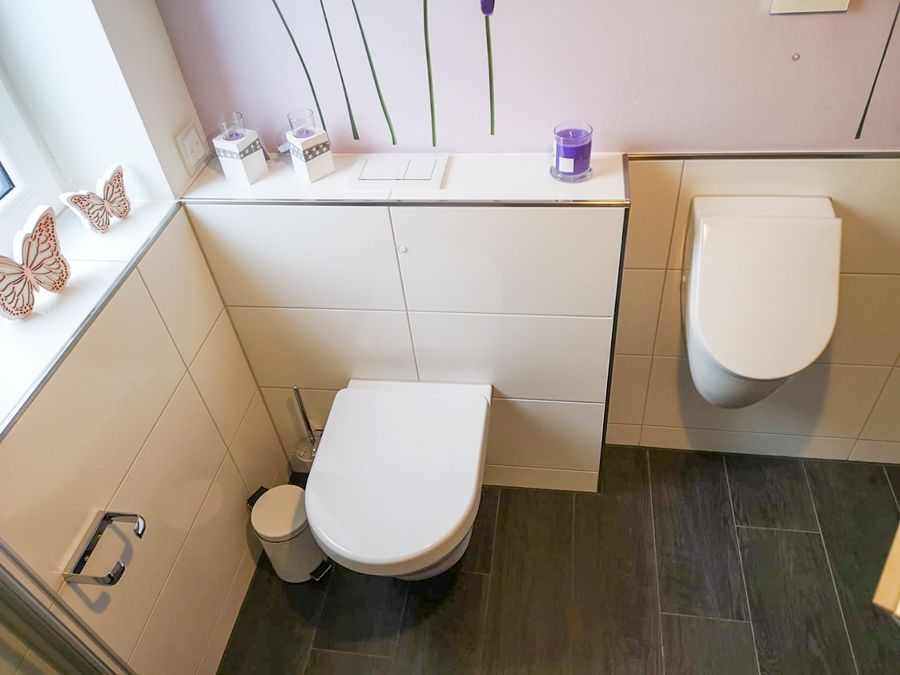 Ein Badezimmer mit zwei Toiletten und einer Kerze auf dem Regal