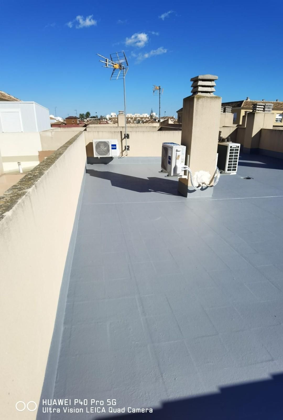 Azotea con unidades de climatización, conductos de ventilación de chimeneas y un cielo azul sobre los edificios cercanos.