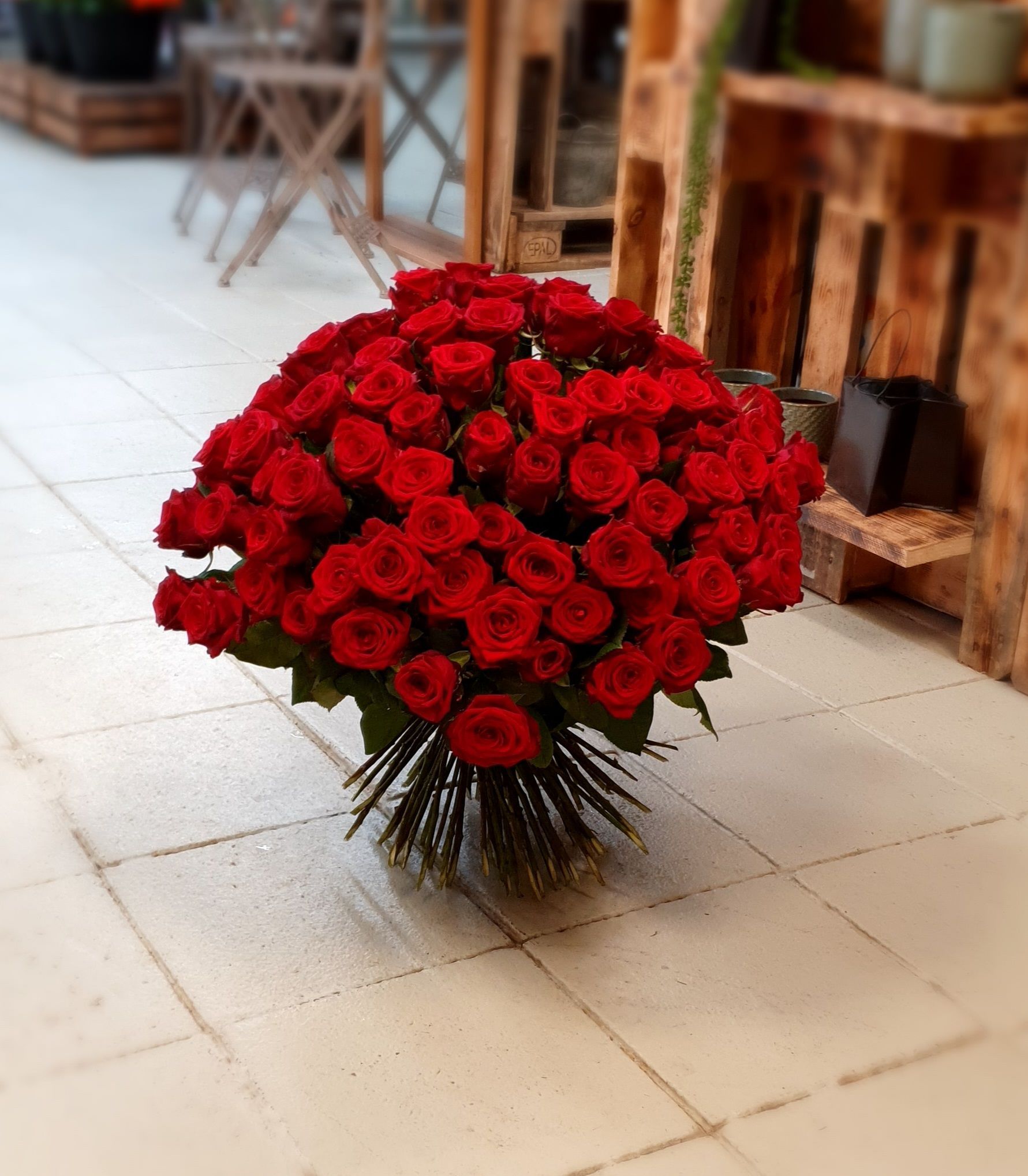 Ein großer Strauß roter Rosen liegt auf einem gefliesten Boden