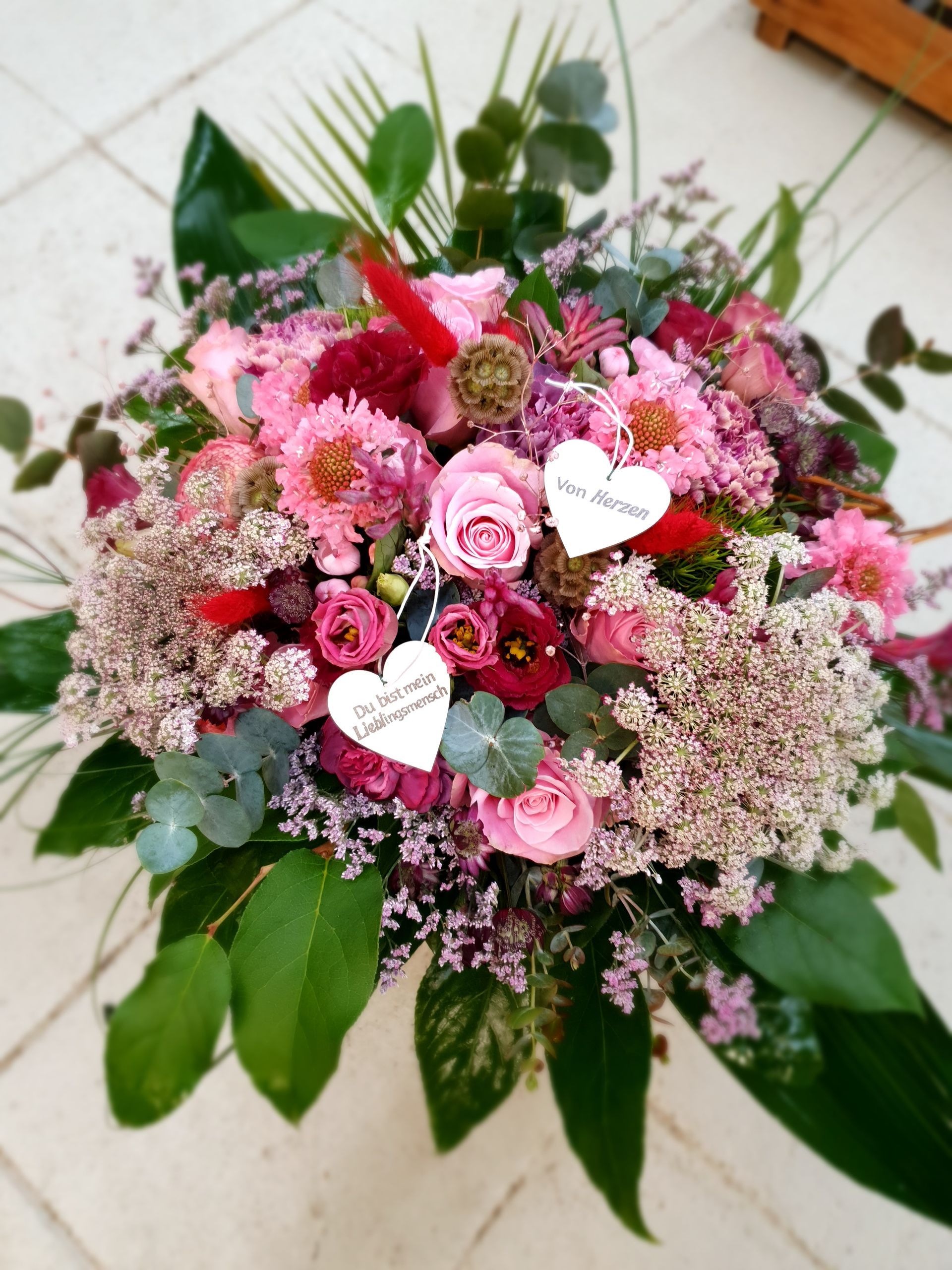 Ein Strauß rosa Blumen mit Herzen darauf