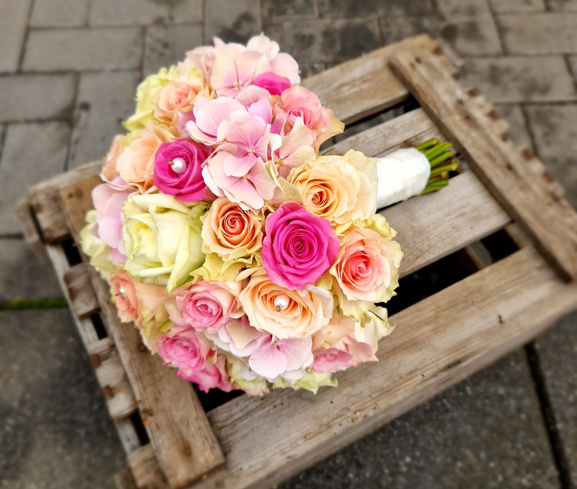 Ein Strauß rosa und weißer Blumen liegt auf einer Holzkiste