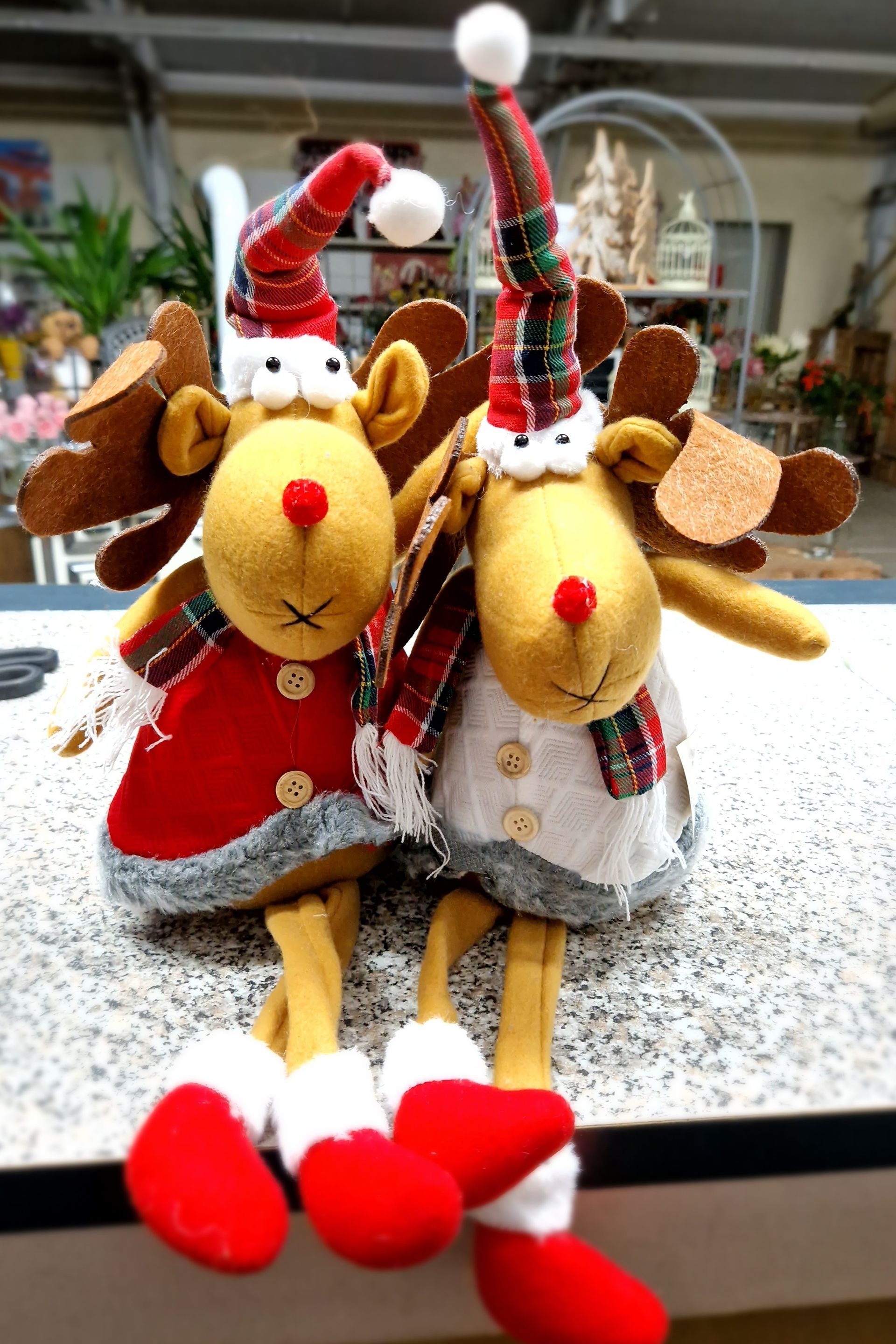 Zwei ausgestopfte Rentiere mit Weihnachtsmannmützen sitzen auf einer Theke.