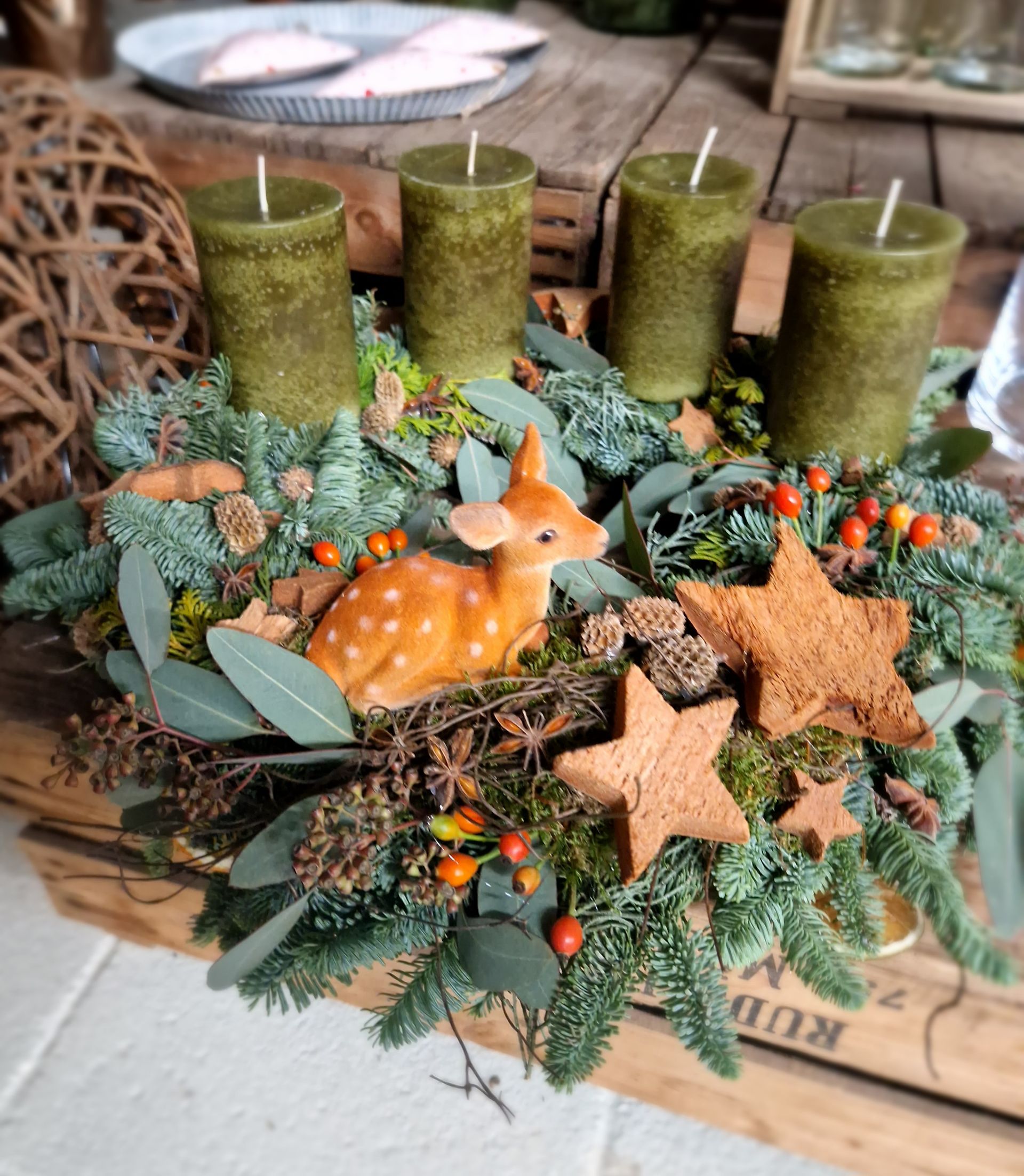 Ein Weihnachtskranz mit Kerzen und einem Hirsch oben drauf