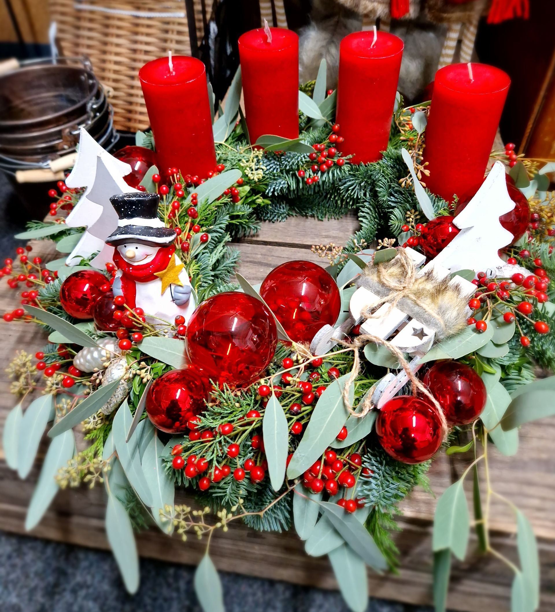 Ein Weihnachtskranz mit roten Kerzen und roten Kugeln