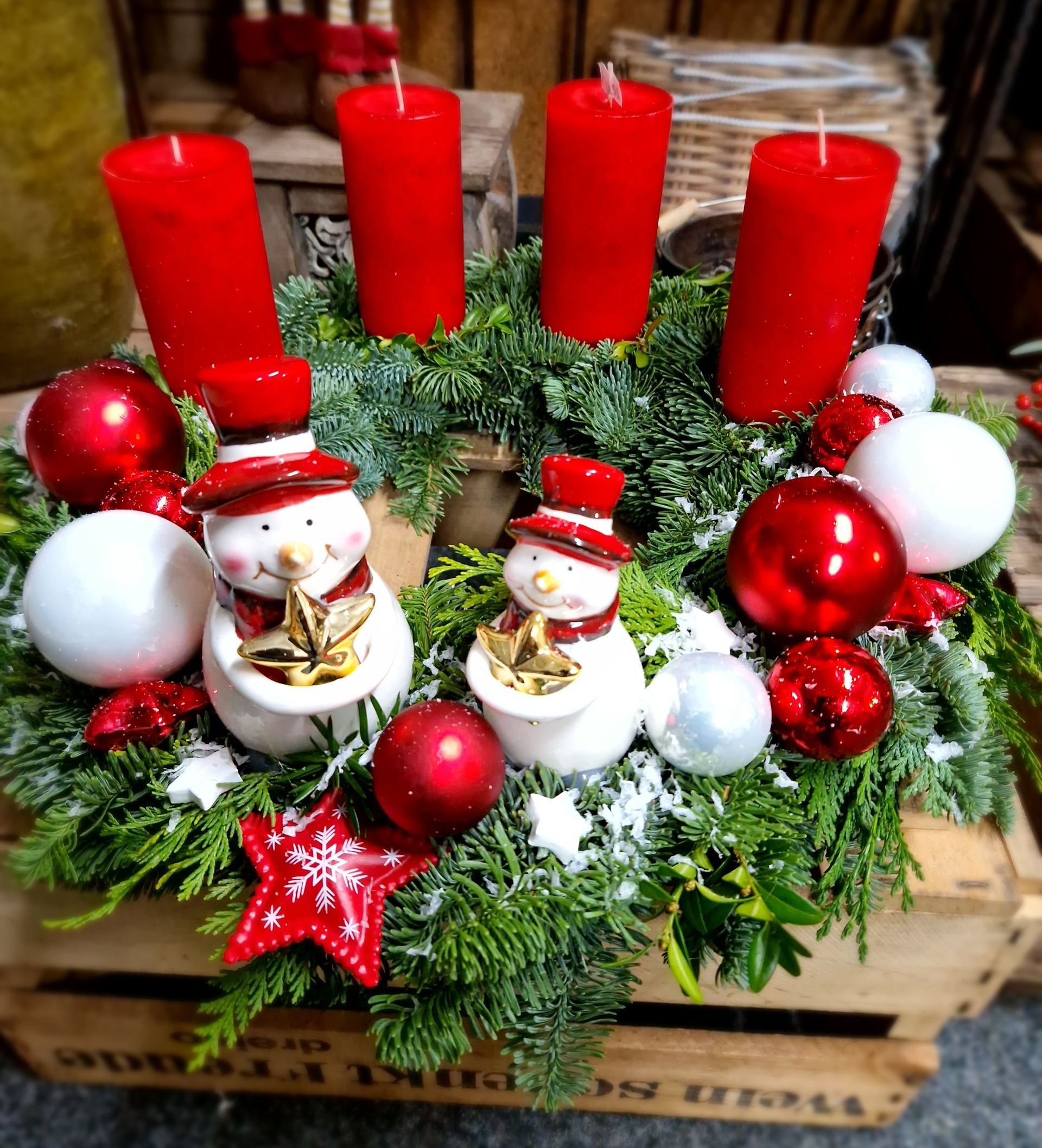 Ein Weihnachtskranz mit roten Kerzen und Schneemännern darauf