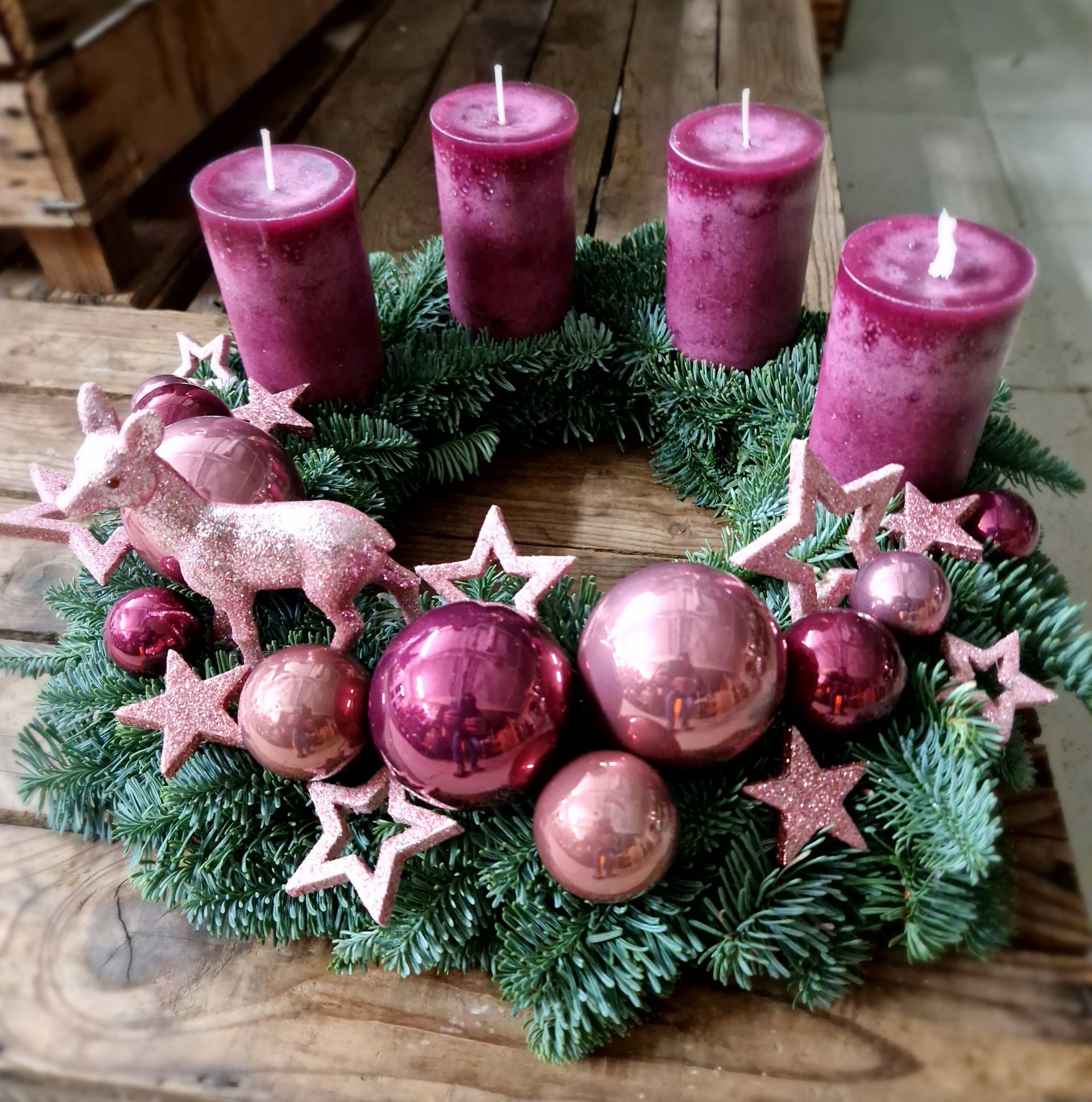 Ein Weihnachtskranz mit lila Kerzen und rosa Ornamenten