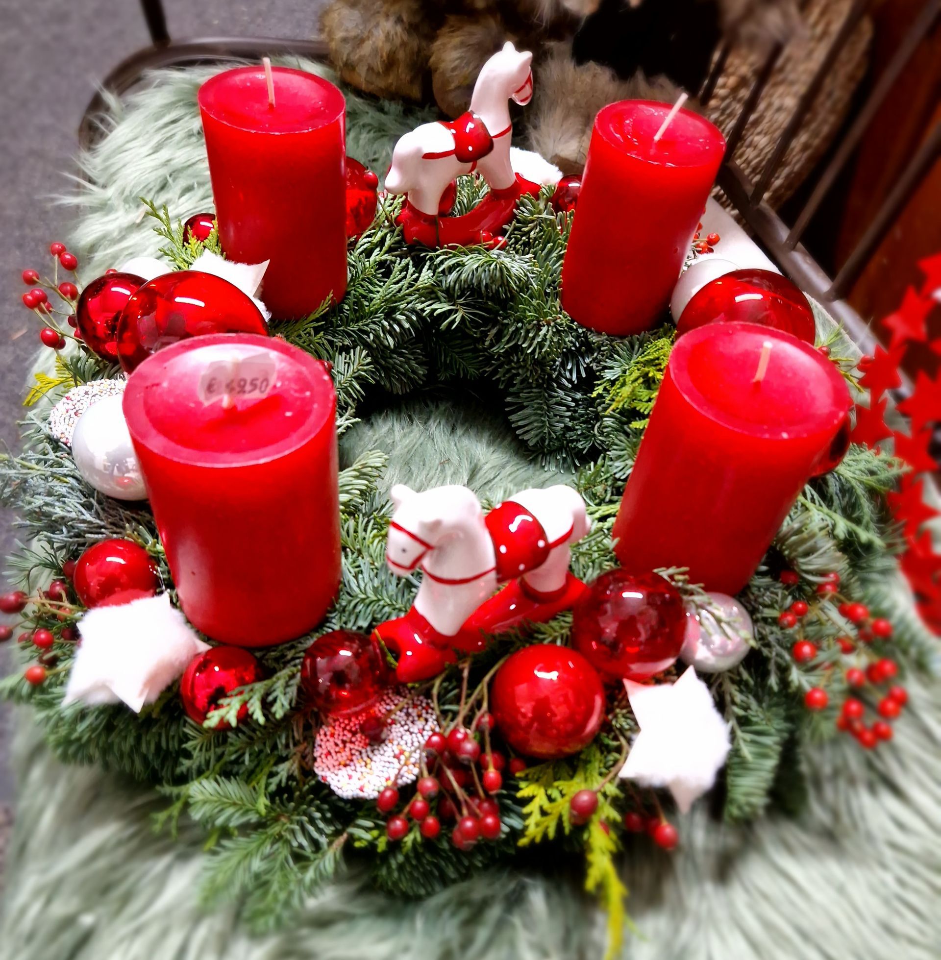 Ein Weihnachtskranz mit roten Kerzen und Schaukelpferden