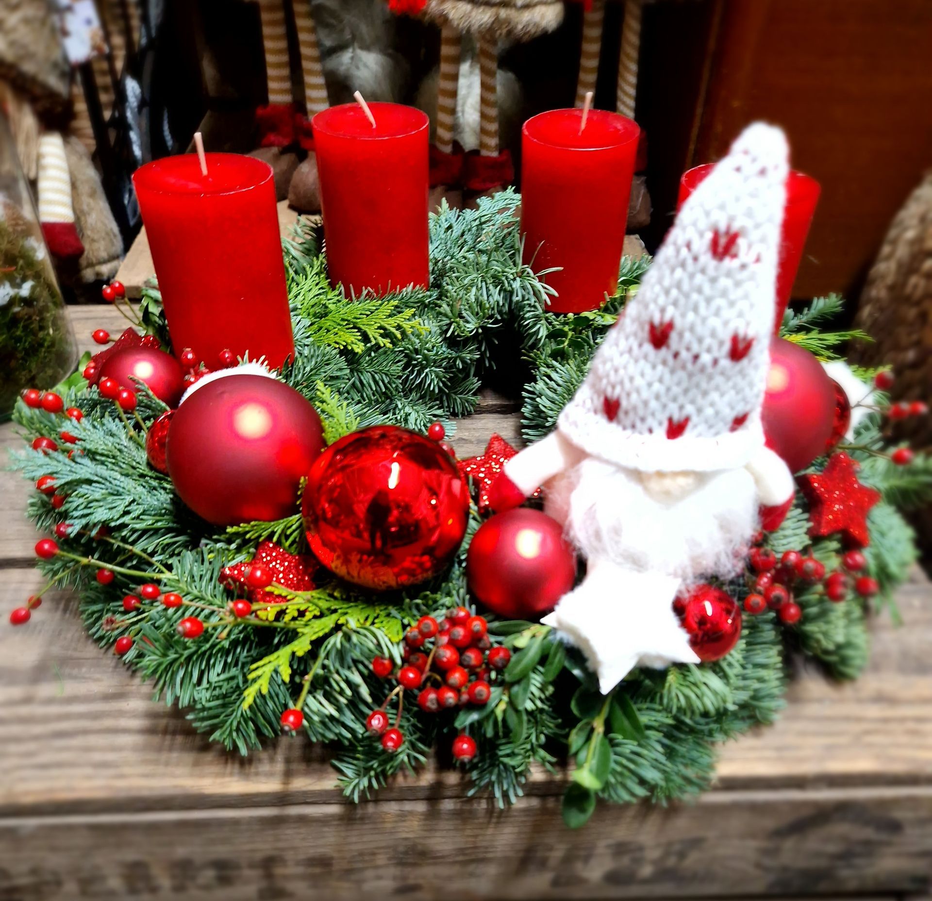 Ein Weihnachtskranz mit roten Kerzen und roten Ornamenten