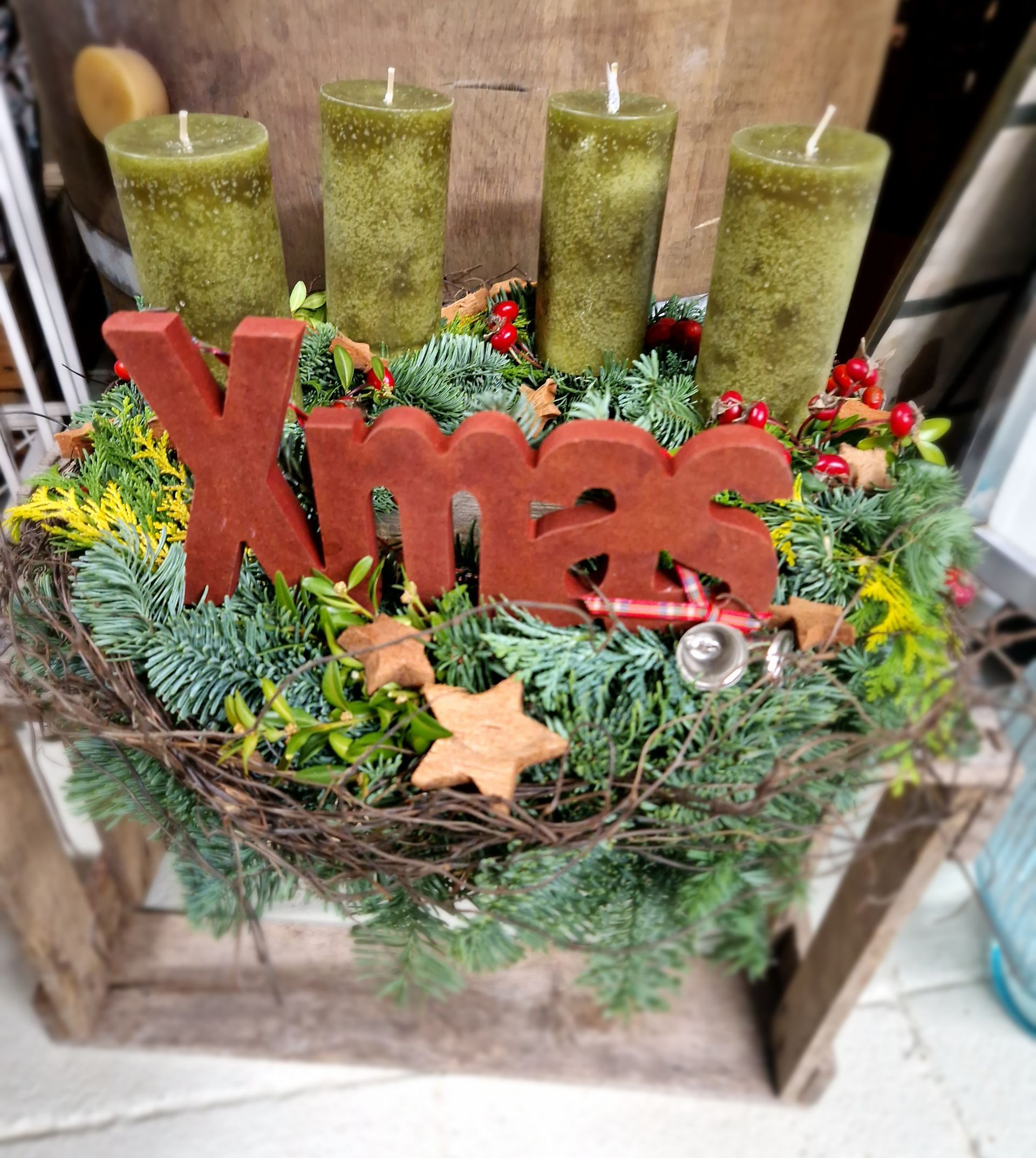 Ein Weihnachtskranz mit grünen Kerzen und einem roten Weihnachtsschild.