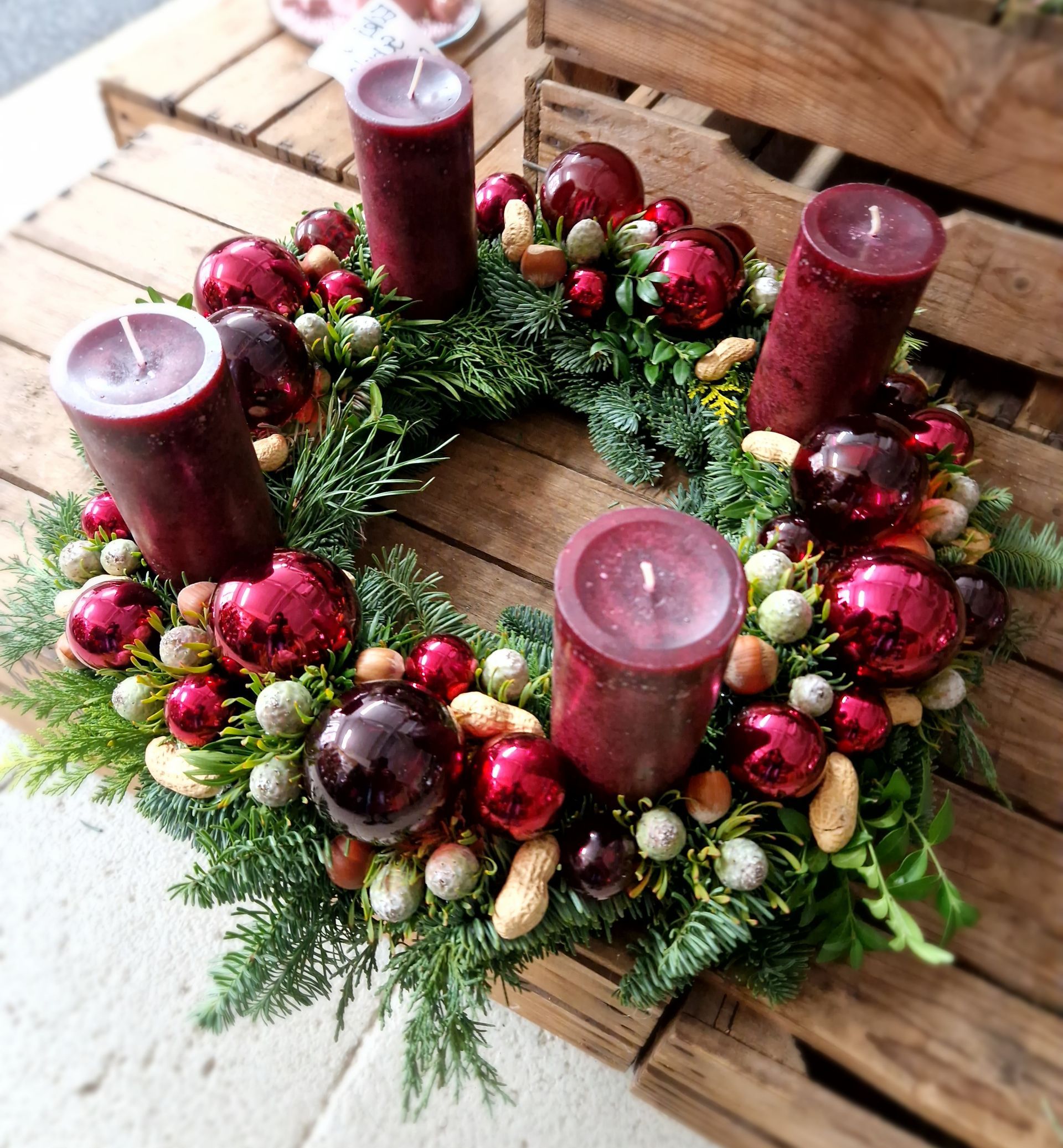 Ein Weihnachtskranz mit Kerzen und Dekorationen auf einem Holztisch