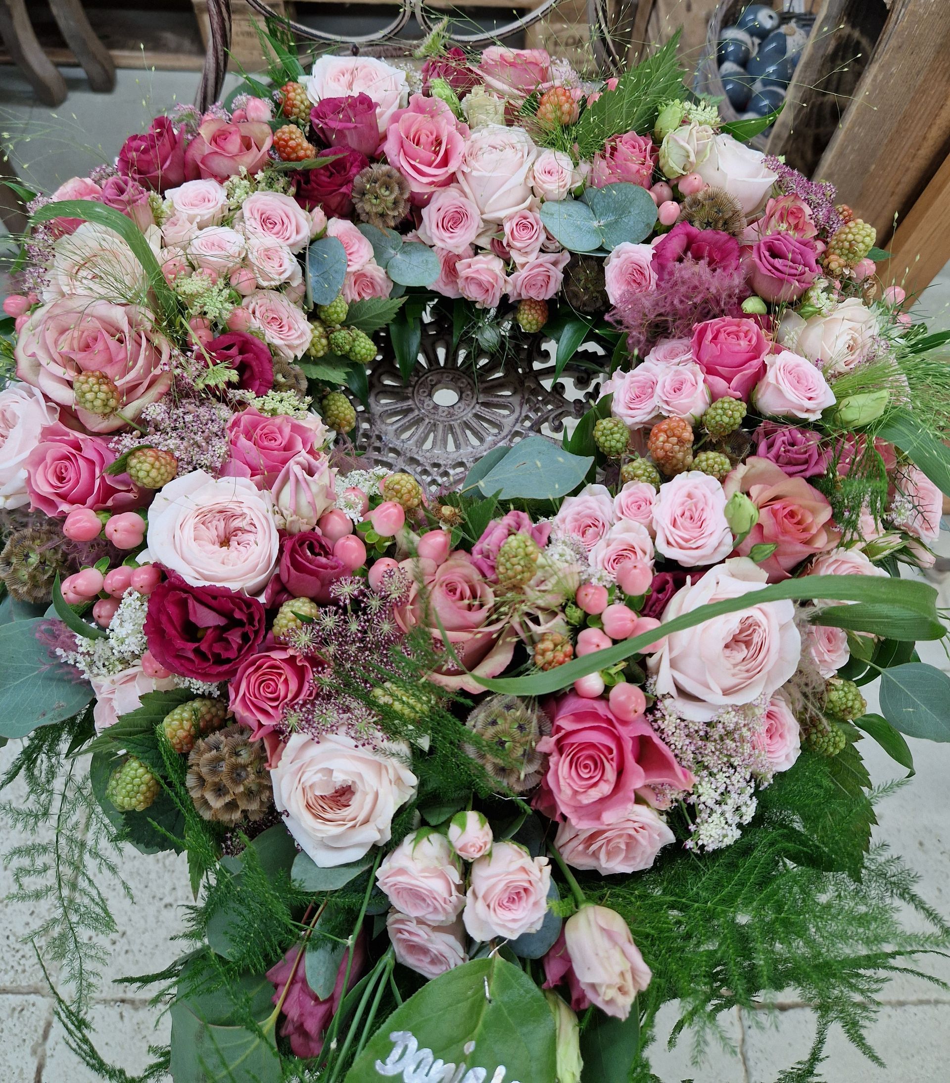 Auf einem Tisch steht ein Kranz aus rosa Blumen.