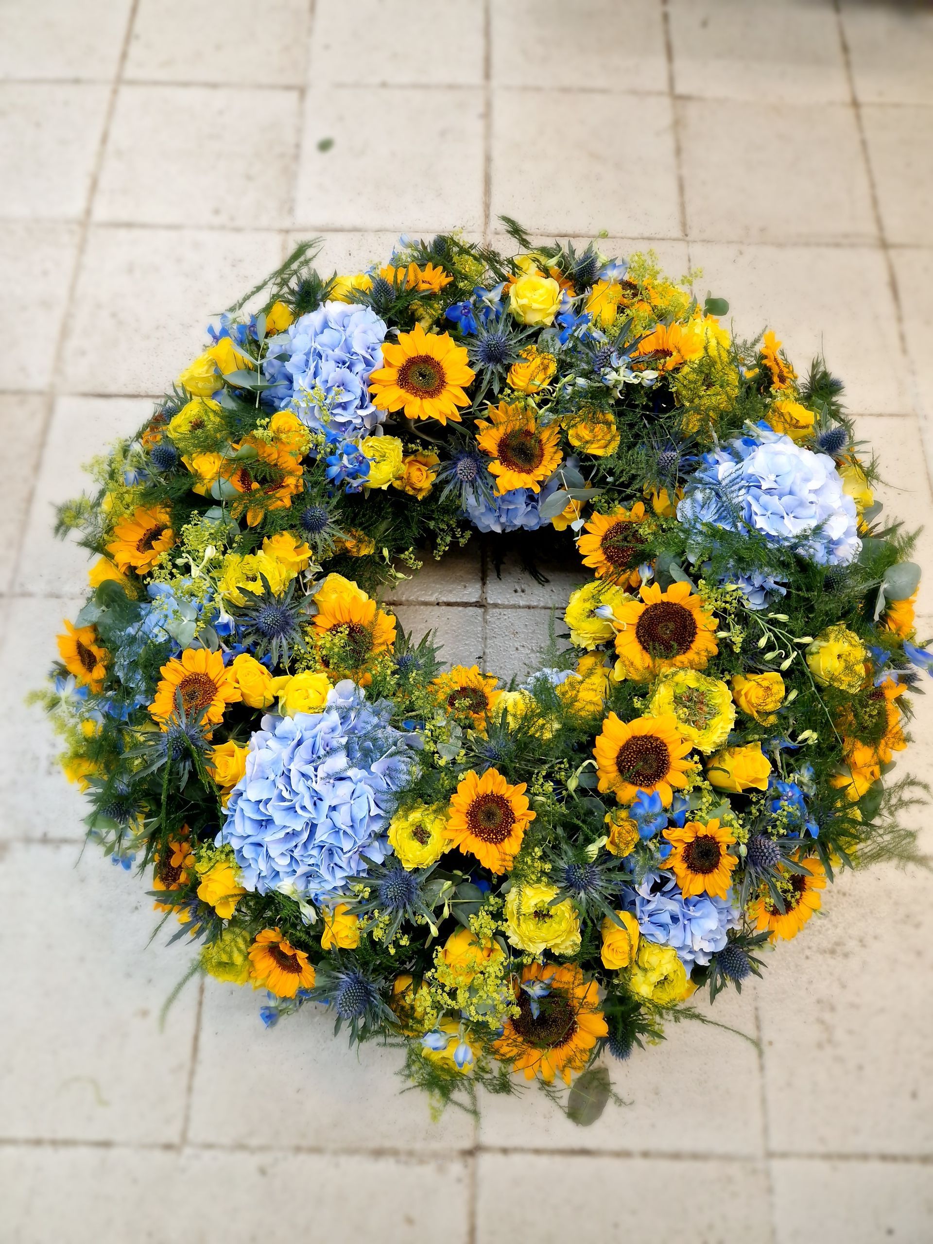 Ein Kranz aus gelben und blauen Blumen auf einem gefliesten Boden