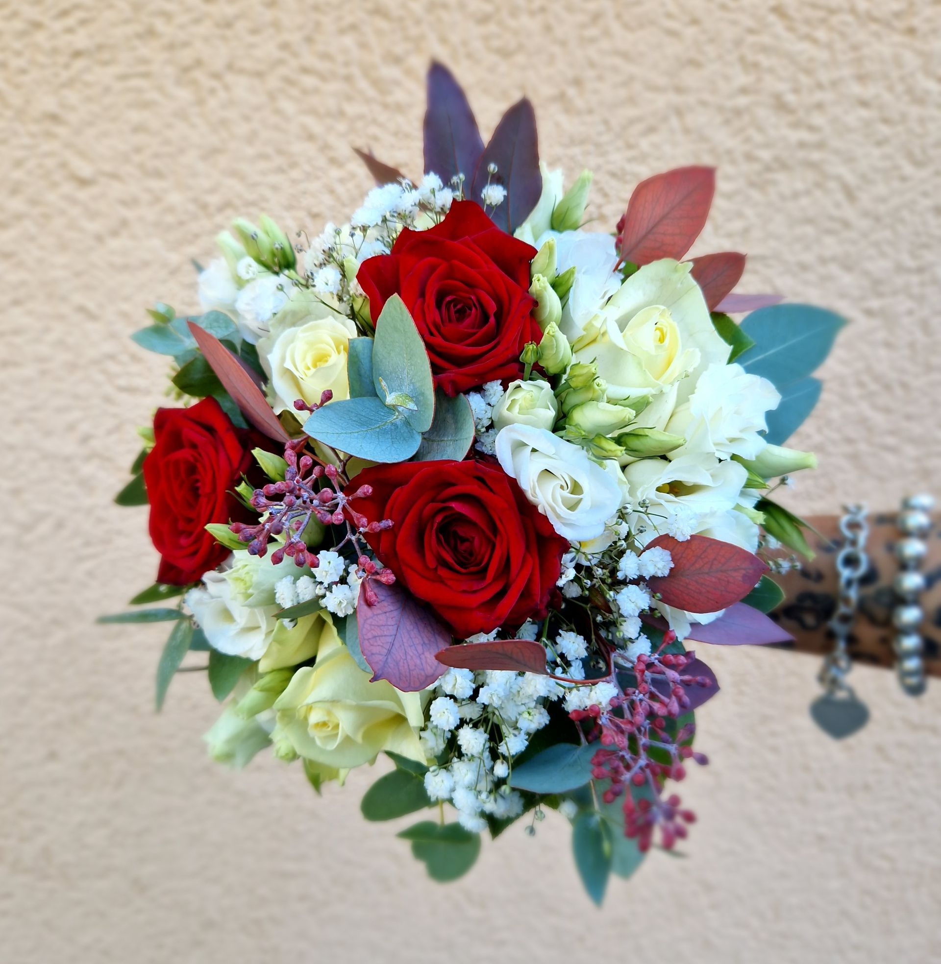 Eine Person hält einen Strauß roter und weißer Blumen